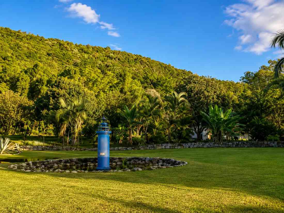 Jardim do hotel com lago e morros de mata ao fundo