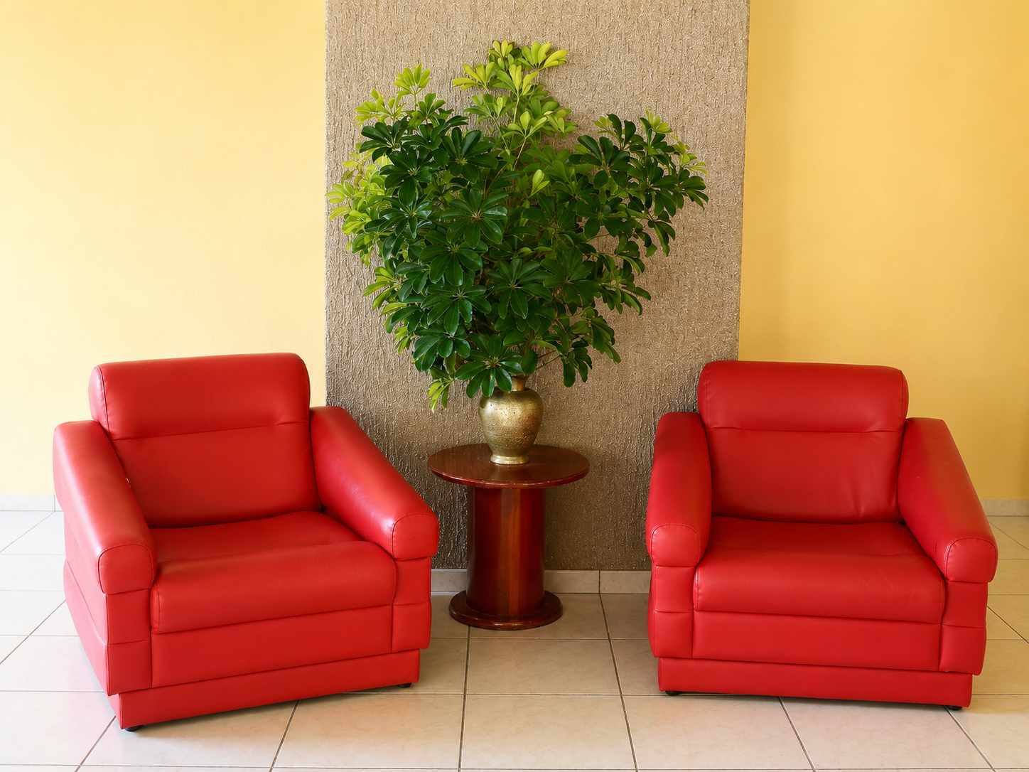 Hotel entrance lounge with red armchairs and a plant against a warm yellow wall