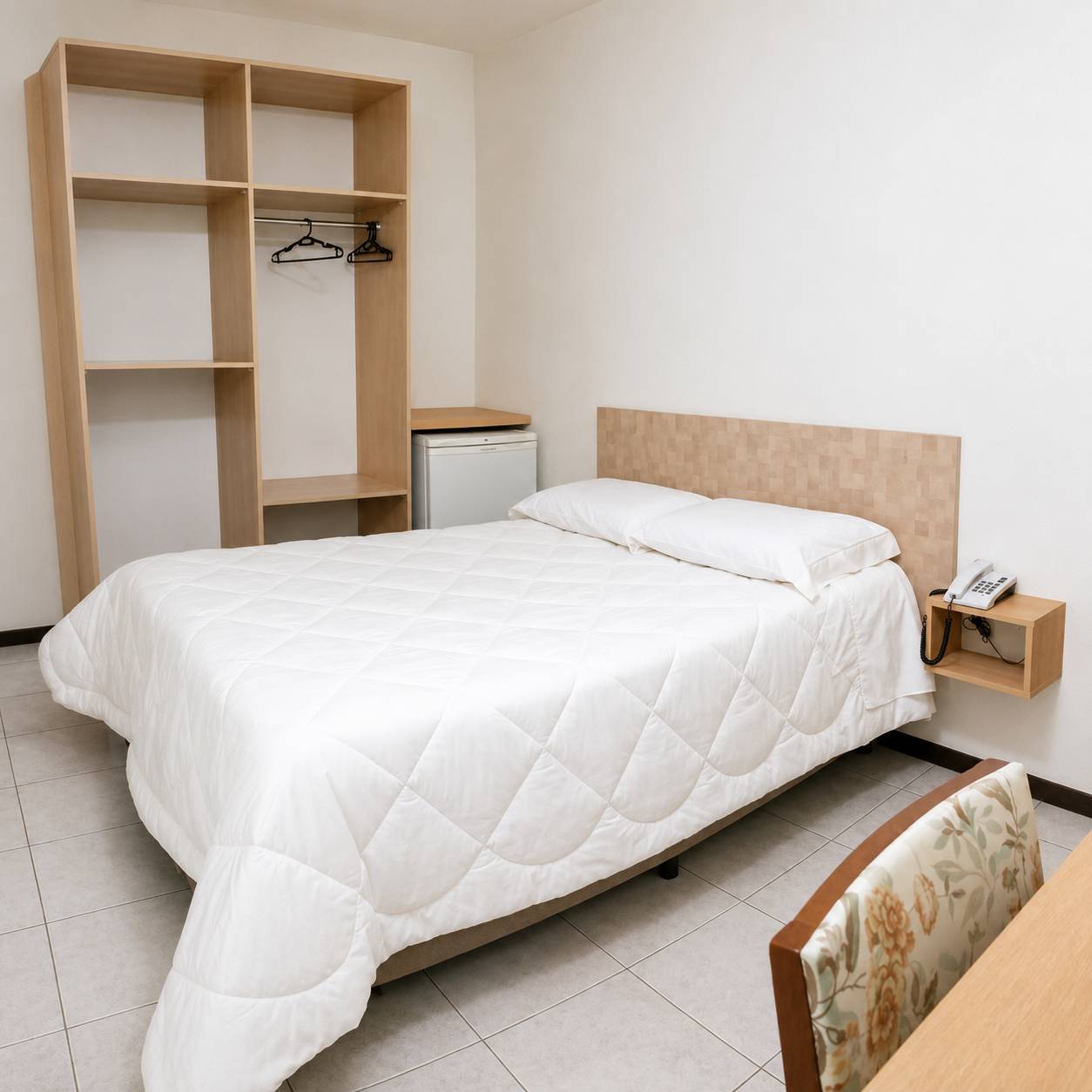 Spacious guest room with a double bed, open wardrobe and mini-bar