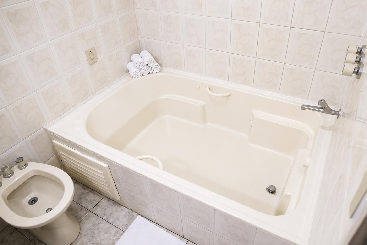 Private bathroom with a large hydromassage spa bath and rolled towels
